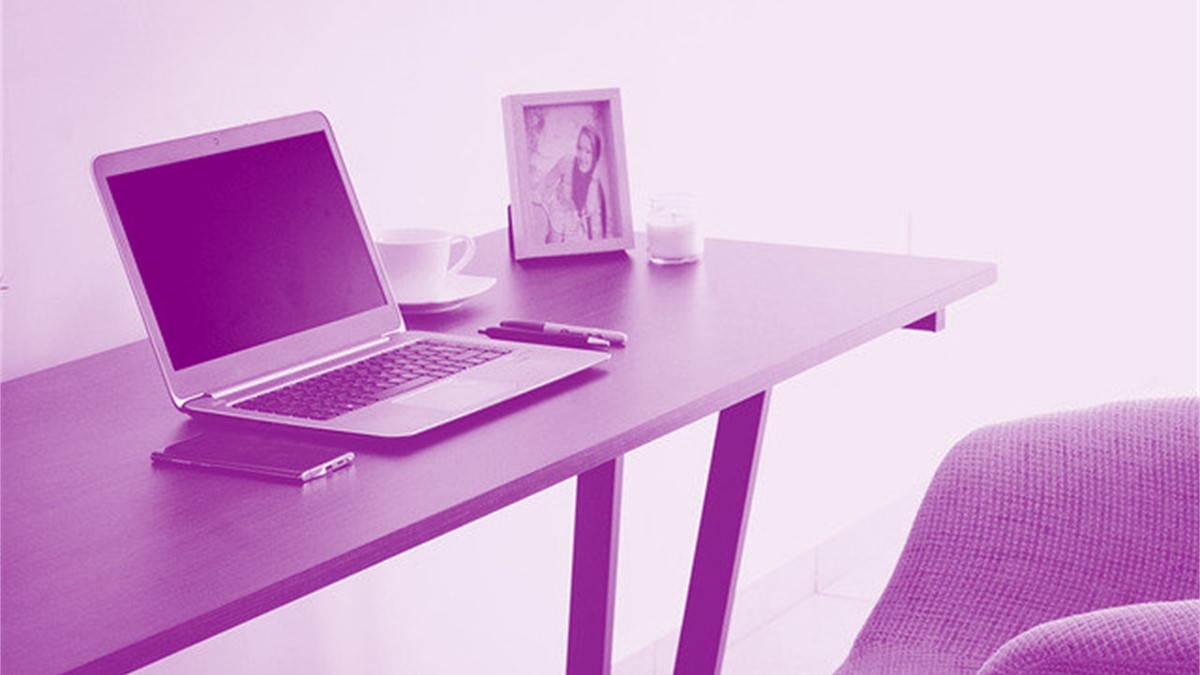 Purple-tinted image of a desk with a laptop, smartphone, pens and paper on it.
