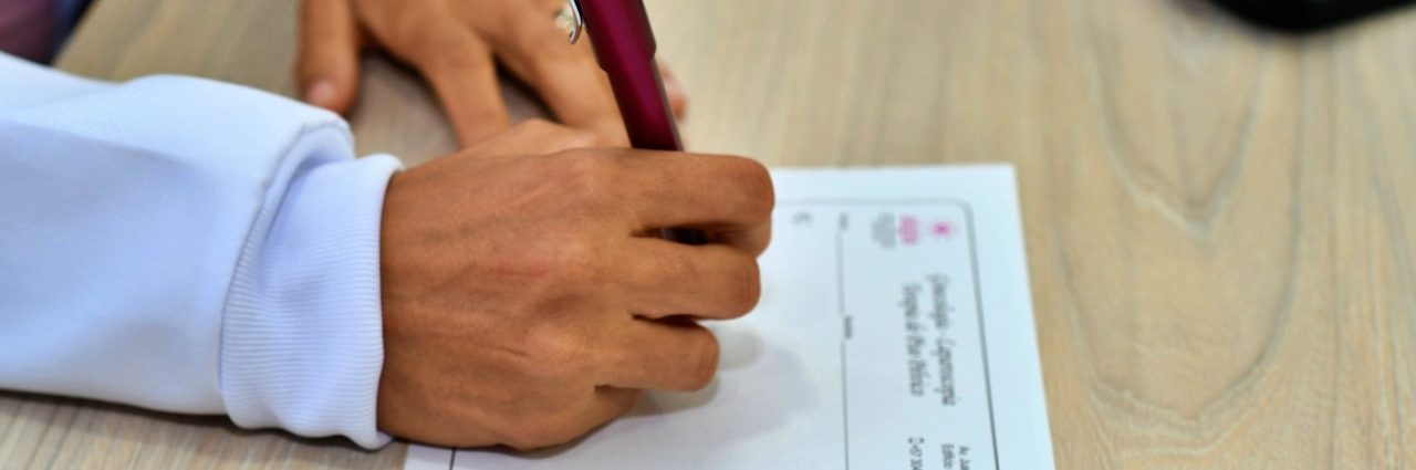 A medical professional filling in a form with a pen