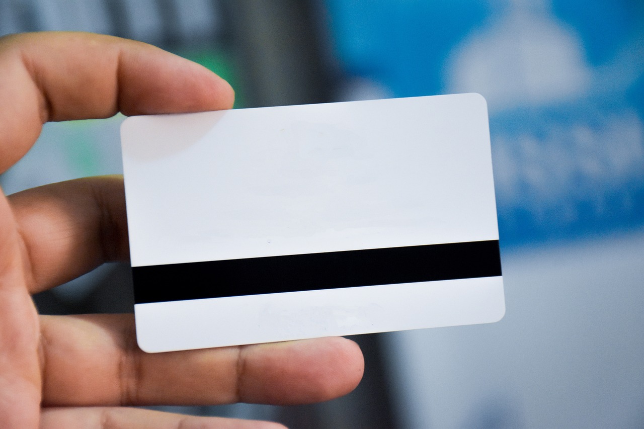 An image of someone holding the back of a card in their hand. The card is mainly white, with a black strip near the bottom.