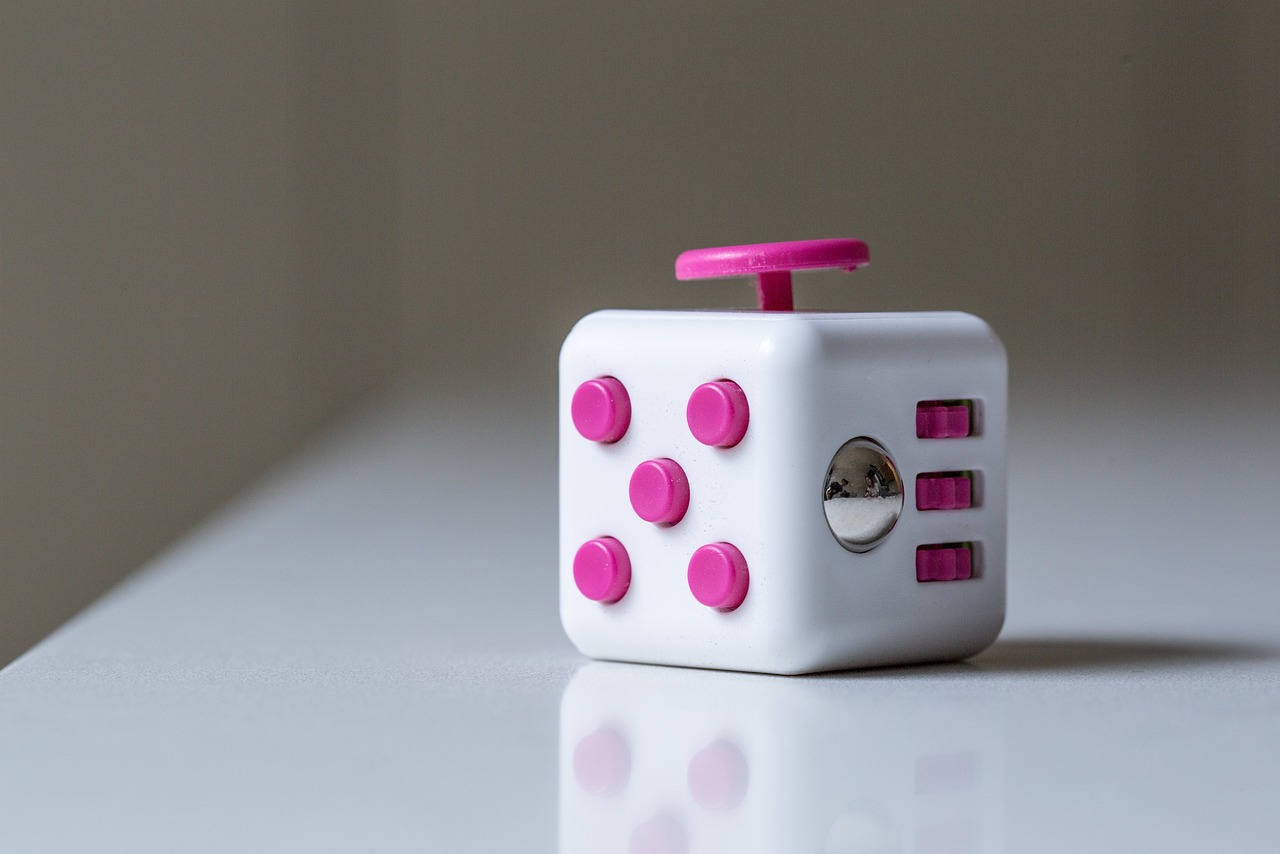 An image of a pink and white fidget cube on top of a white table.