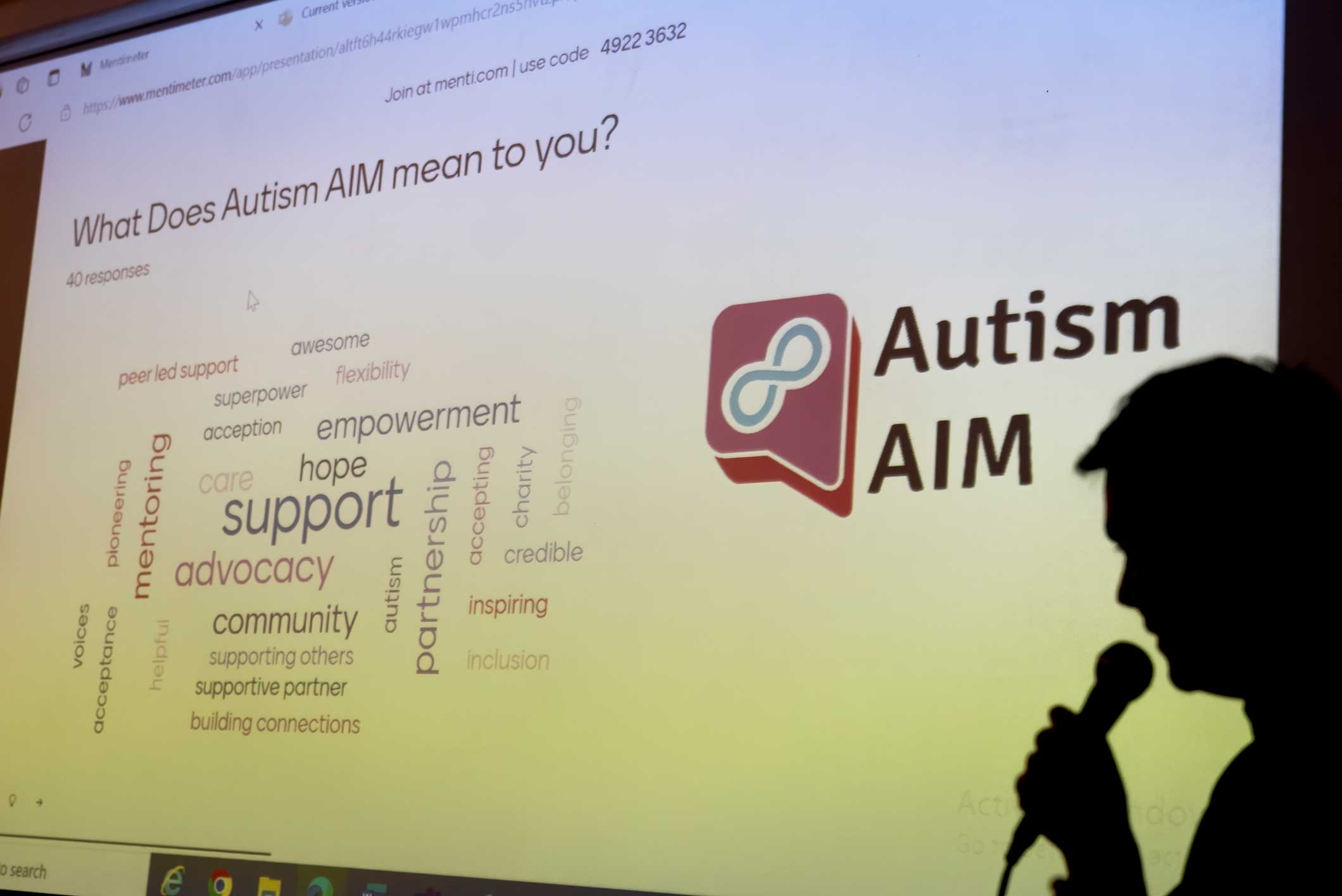 A silhouette of Owen, our Manager, speaking at an event with a projector screen behind him.